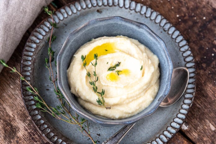 Ein Schüsselchen mit Selleriepüree mit Trüffelöl und einem Zweig Thymian