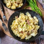 Zwei Pfannen mit Krautfleckerl auf einem Brett mit Schnittlauch