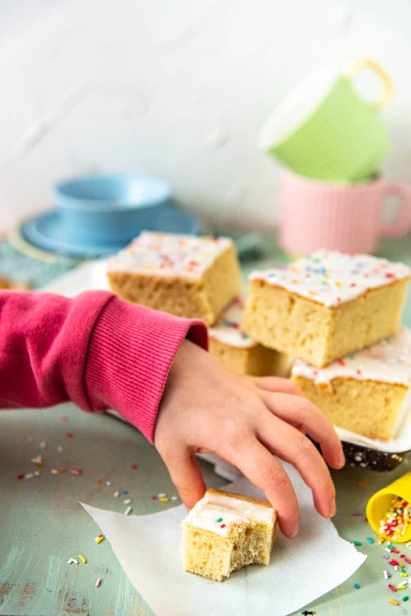 Eine Kinderhand greift zu einem Stück Fantakuchen