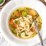 Flädlelsuppe in einem Suppenteller mit Löffel und Schnittlauch