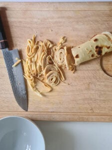 Pfannkuchen für Frittatensuppe wird in Streifen geschnitten