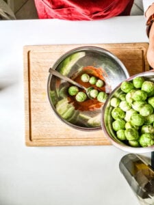 Rosenkohl wird mit Gewürzen vermischt für Rezept Rosenkohl Ofen