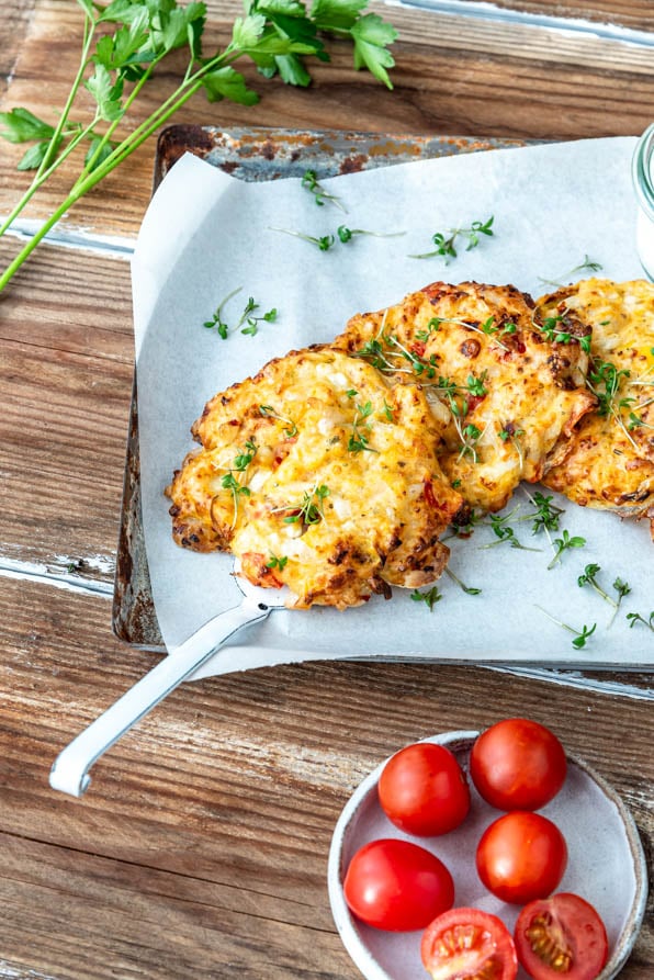 Hüttenkäsetaler mit Dip auf Blech und einer Schüssel Tomaten