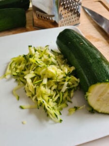 eine geriebene Zucchini für Zucchinipuffer auf einem Teller