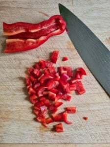 würfelig geschnittene Paprika auf Holzbrett für Zucchinipuffer