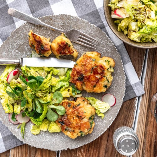 Kaspressknödel mit Salat und einem Glas Wein auf Holztisch