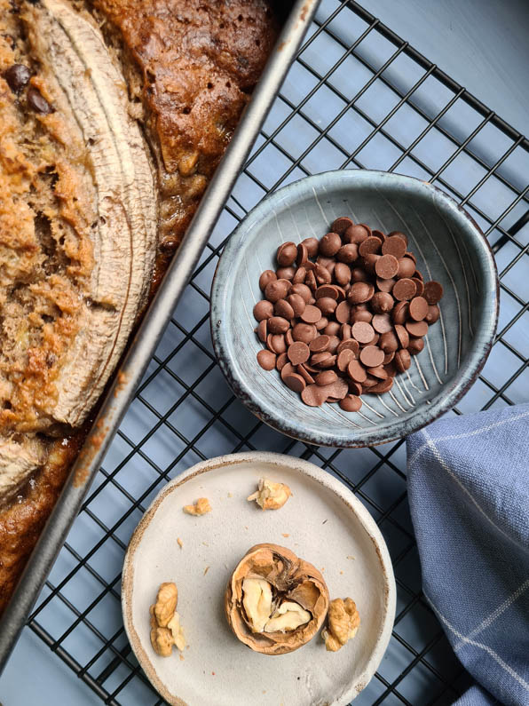 Schokotröpfchen und Walnuss neben Kuchen auf Kuchengitter