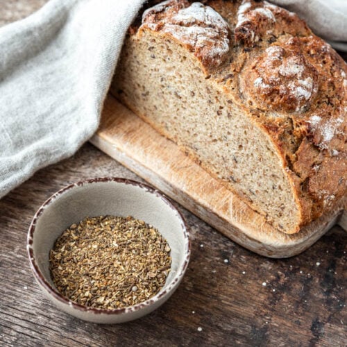 Ein Schälchen Brot Gewürz neben einem Laib Brot