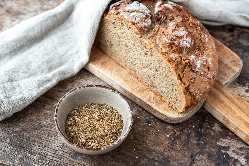 Ein Schälchen Brot Gewürz neben einem Laib Brot