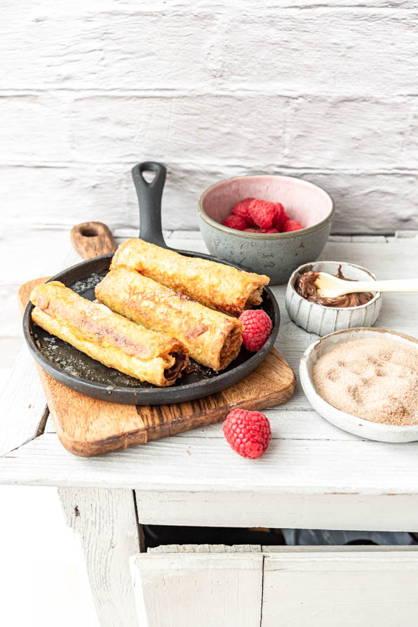 French Toast Röllchen in Pfanne auf Holzbrettchen