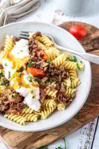 Ein Teller türkische Pasta auf einem Brettchen und Tomaten