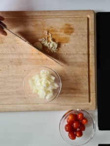 Zwiebel und Knoblauch wird auf Holzbrett gehackt