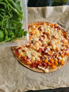 Rucola wird über Pizza gegeben