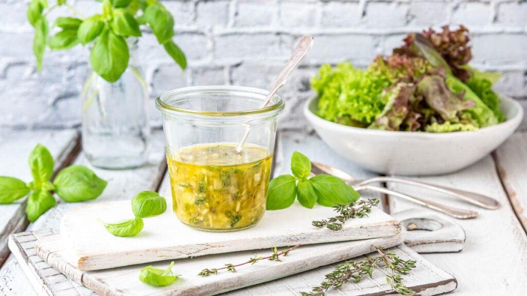 Italian Dressing in Glas mit Salat im Hintergrund - Foodblog Mundgefühl