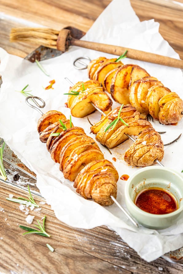 Spiralkartoffeln auf Spießen auf Tablett und Rosmarinzweigen