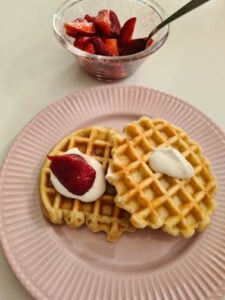 belgische Waffeln auf Teller mit Sahne und Erdbeeren