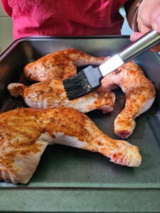 Hähnchenschenkel werden mit Marinade bestrichen