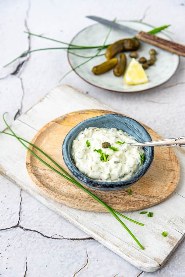 Schälchen mit Sauce Tartare auf Holzteller und Cornichons