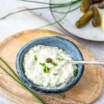 Schälchen mit Sauce Tartare auf Holzteller und Cornichons