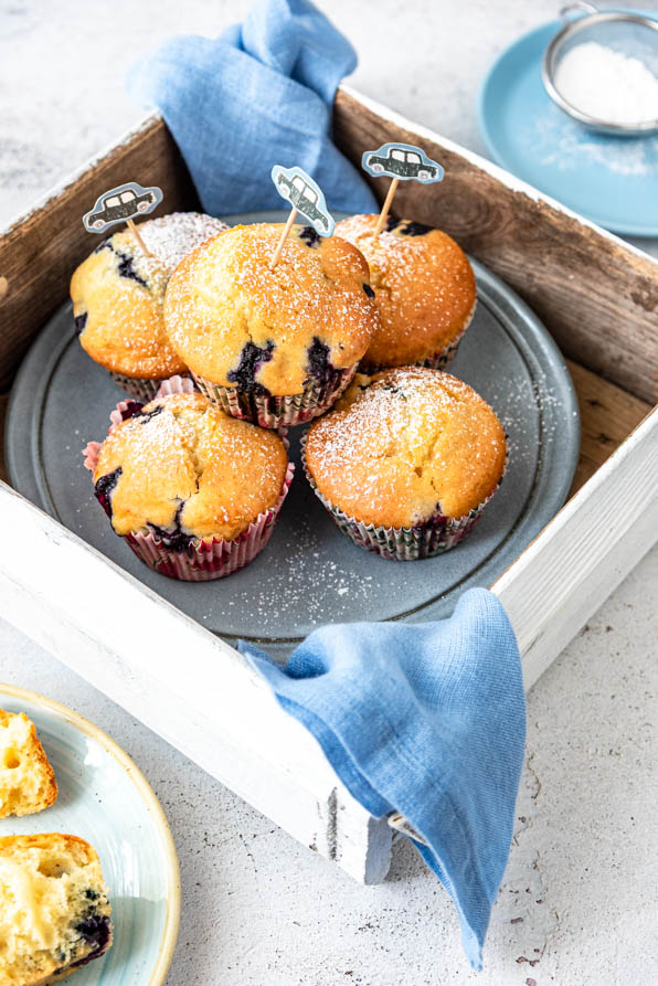 Blaubeermuffins auf Teller in Holzbox mit kindlicher Deko