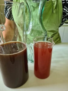 Eine Karaffe mit schwarzem Tee und eine mit Pfirsichsaft für hausgemachten Eistee