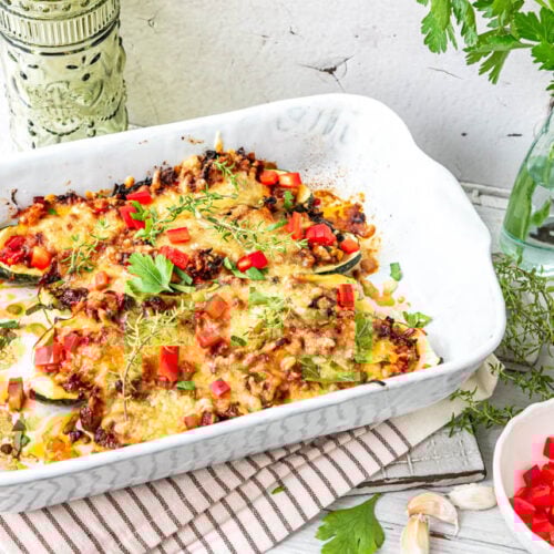 Low-Carb Zucchini-Schiffchen vegetarisch gefüllt in weißer Auflaufform