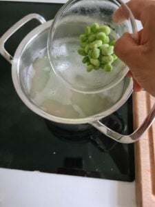 Gefrorene Edamame werden zu Kritharaki Nudeln ins Kochwasser gegeben