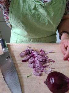 rote Zwiebel wird auf Holzbrett geschnitten