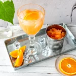 Aperol Drink mit Eis auf Tablett.