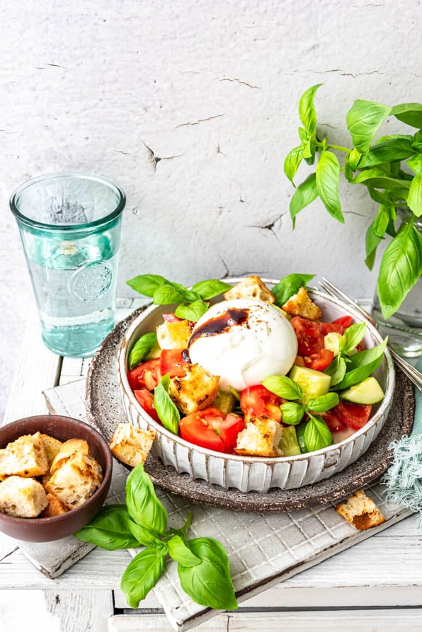 Italienischer Brotsalat angerichtet. Daneben ein Glas und ein Schüsselchen Croutons