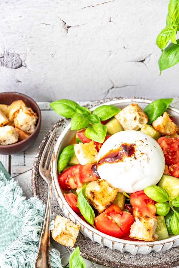 Panzanella mit Burrata hübsch angerichtet. Daneben Croutons