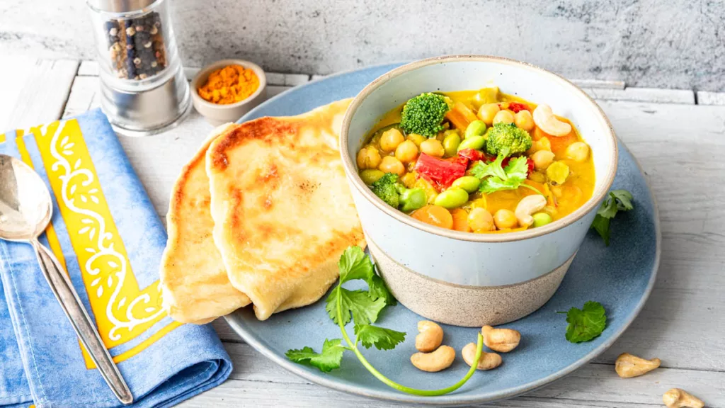 Frisches Kichererbsen-Curry mit Fladenbrot auf Teller