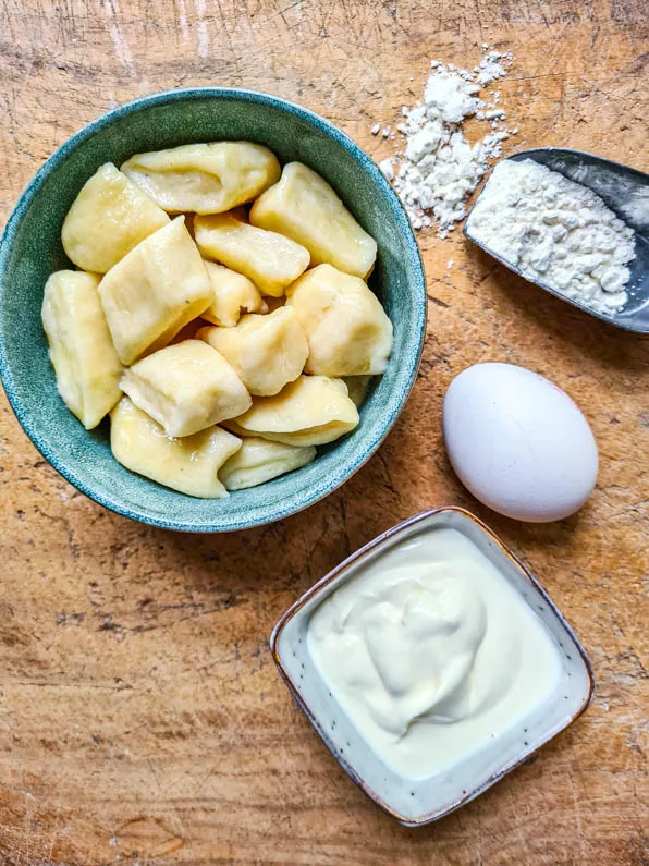 Fertig gekochte Gnocchi und daneben die Zutaten Mehl, Ei und Quark