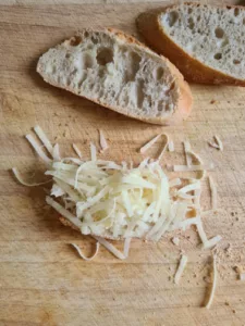 Baguettescheiben werden mit Butter bestrichen und mit Käse bestreut