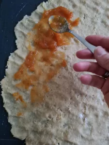 Aprikosenmarmelade wird dünn auf den Mürbeteig gestrichen