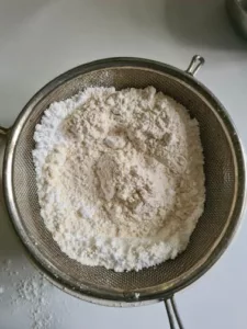 Mehl für Rezept Puddingplätzchen wird gesiebt.