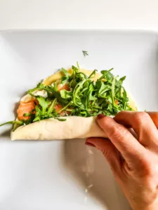 Pfannkuchen mit Lachs und Frischkäse wird eng zu einer Rolle eingerollt