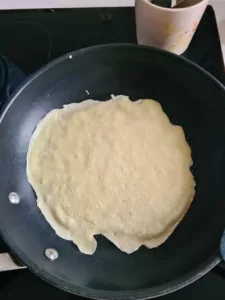 Pfannkuchen backt in der Pfanne, bis sich die Ränder leicht lösen