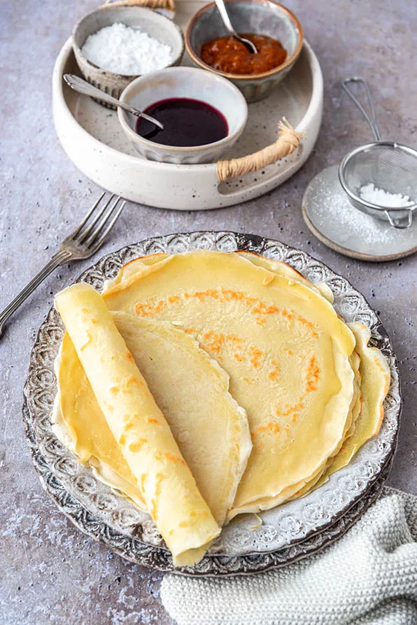 Selbstgemachte Pfannkuchen aus einem einfachen Grundrezept, serviert mit Marmelade und Puderzucker