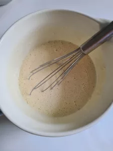 Eier, Milch und Mehl werden in einer Schüssel zu einem glatten Pfannkuchenteig verrührt