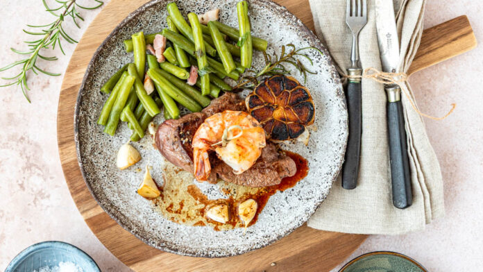 surf-and-turf Surf and Turf mit saftigem Rindersteak und gebratener Garnele, serviert mit grünen Bohnen