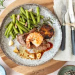 Steak und Garnele als Surf and Turf serviert mit Bohnen und Knoblauch