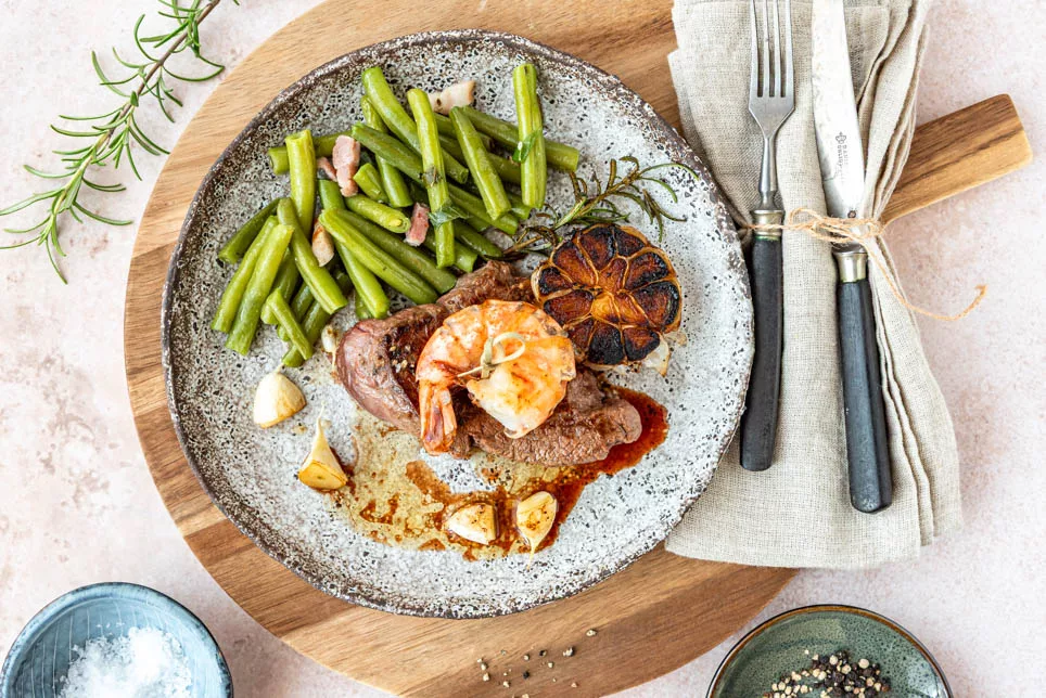 Steak und Garnele als Surf and Turf serviert mit Bohnen und Knoblauch