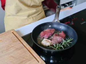 Rindersteak wird mit Knoblauch in einer heißen Pfanne scharf angebraten