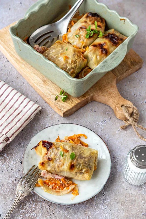 Klassische Kohlrouladen im Ofen gegart, serviert in einer Auflaufform und auf dem Teller angerichtet