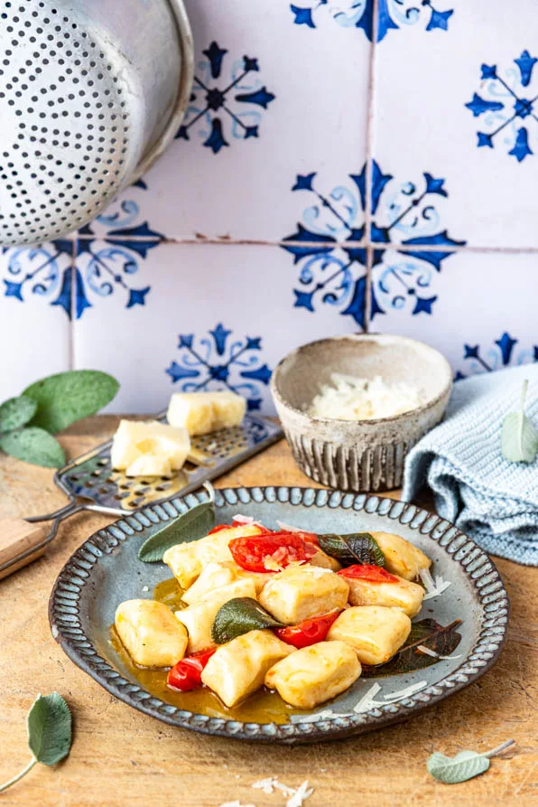 Gnocchi Pfanne mit Butter, Kirschtomaten und Salbei auf grauem Teller mit Parmesan