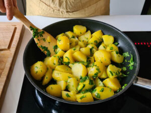 Petersilienkartoffeln werden in Butter mit frischer Petersilie in der Pfanne geschwenkt