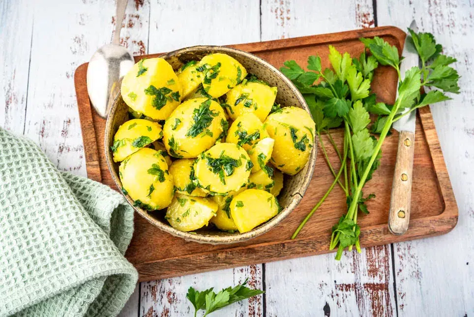 Gekochte Kartoffeln mit Butter und gehackter Petersilie als aromatische Beilage