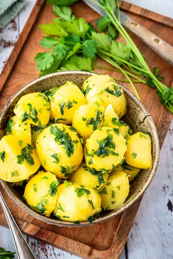 Butterglänzende Kartoffeln mit frischer Petersilie in rustikalem Setting