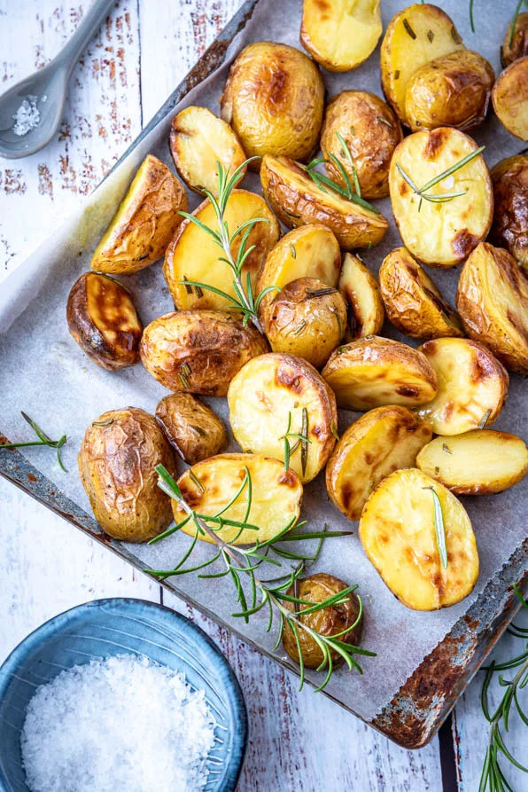 Nahaufnahme von halbierten Ofenkartoffeln mit Olivenöl und Rosmarin, goldbraun geröstet und außen knusprig